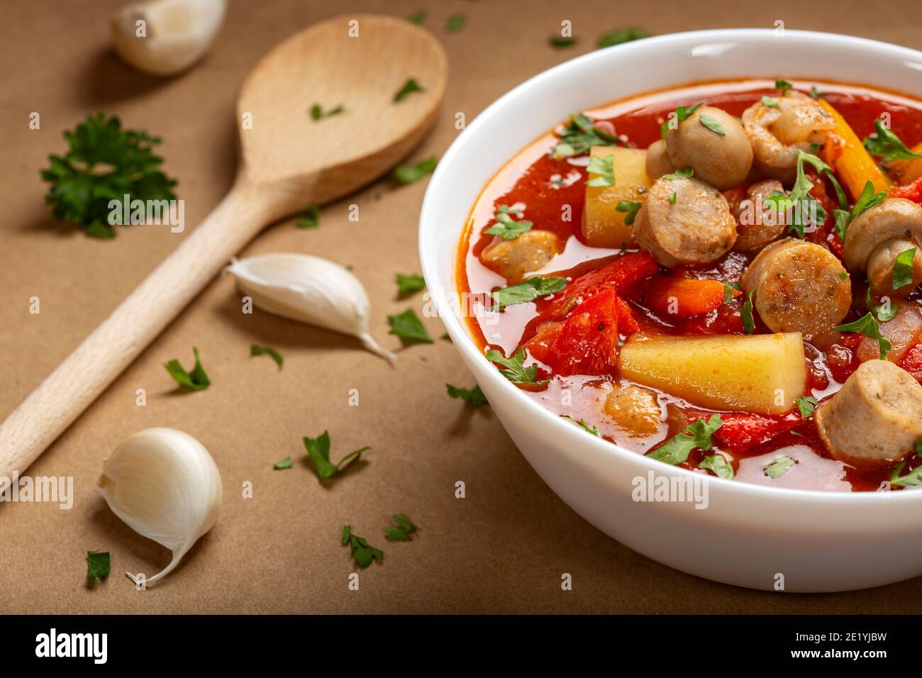 Suppe mit Schweinewurst und frischem Gemüse in Schüssel mit Kräuter Stockfoto