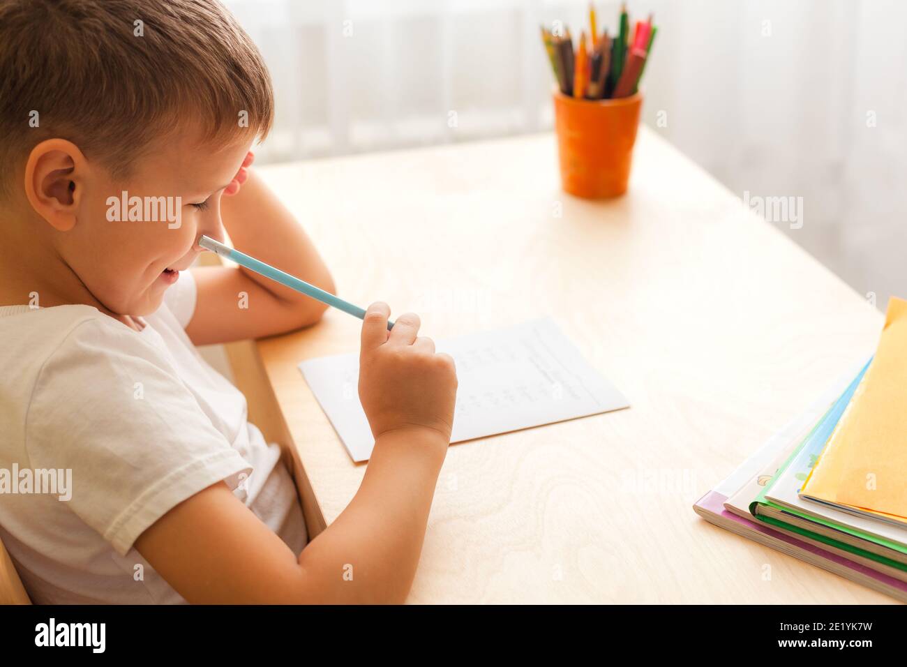 7 Jahre alt Kind Junge zu Hause arbeiten sitzen am Schreibtisch in seinem Zimmer. Stockfoto