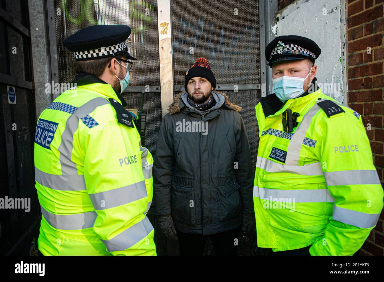 Ein Protestler wird von der Polizei in der Clapham High Street während der Anti-Lockdown-Demonstration am 9. Januar 2021 in London, England, verhört Stockfoto