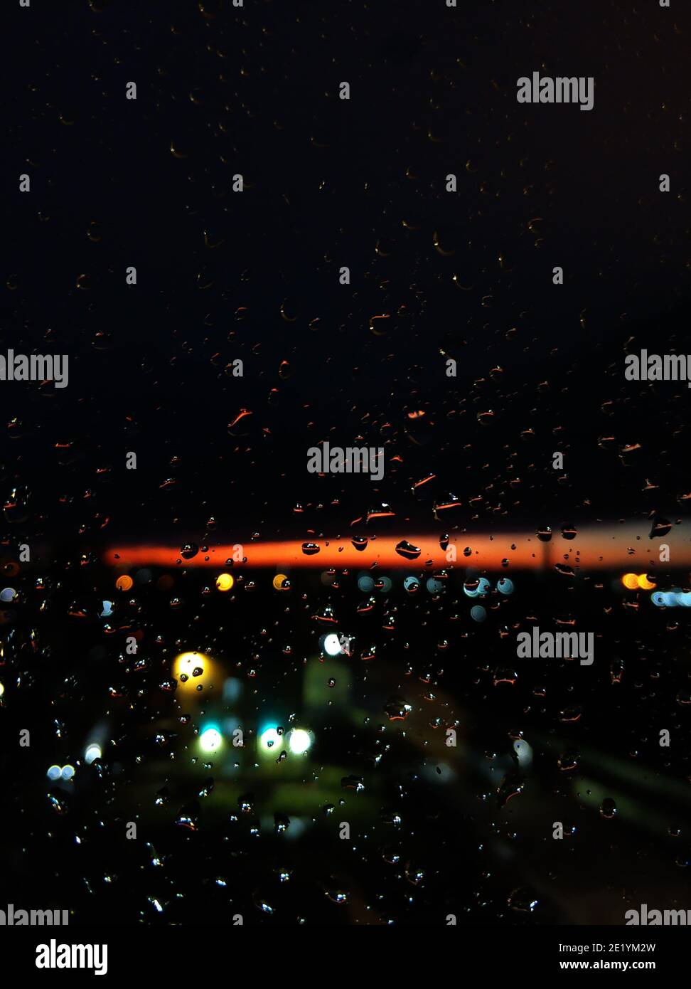 Regentropfen auf Glas. Livin bei Sonnenuntergang. Nachthimmel mit einem leuchtend orangefarbenen Streifen. Stockfoto