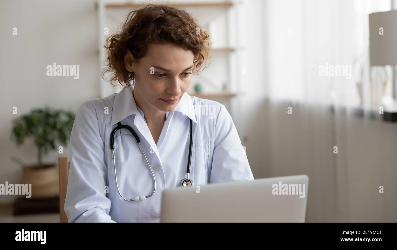 Fokussierte junge weibliche 35s Arzt, der am Computer arbeitet. Stockfoto