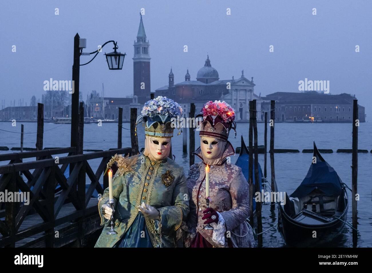 Frau in traditionell dekoriertem Kostüm und Maske während des Karnevals in Venedig gekleidet mit dem Kloster San Giorgio im Hintergrund Venedig, Italien Stockfoto