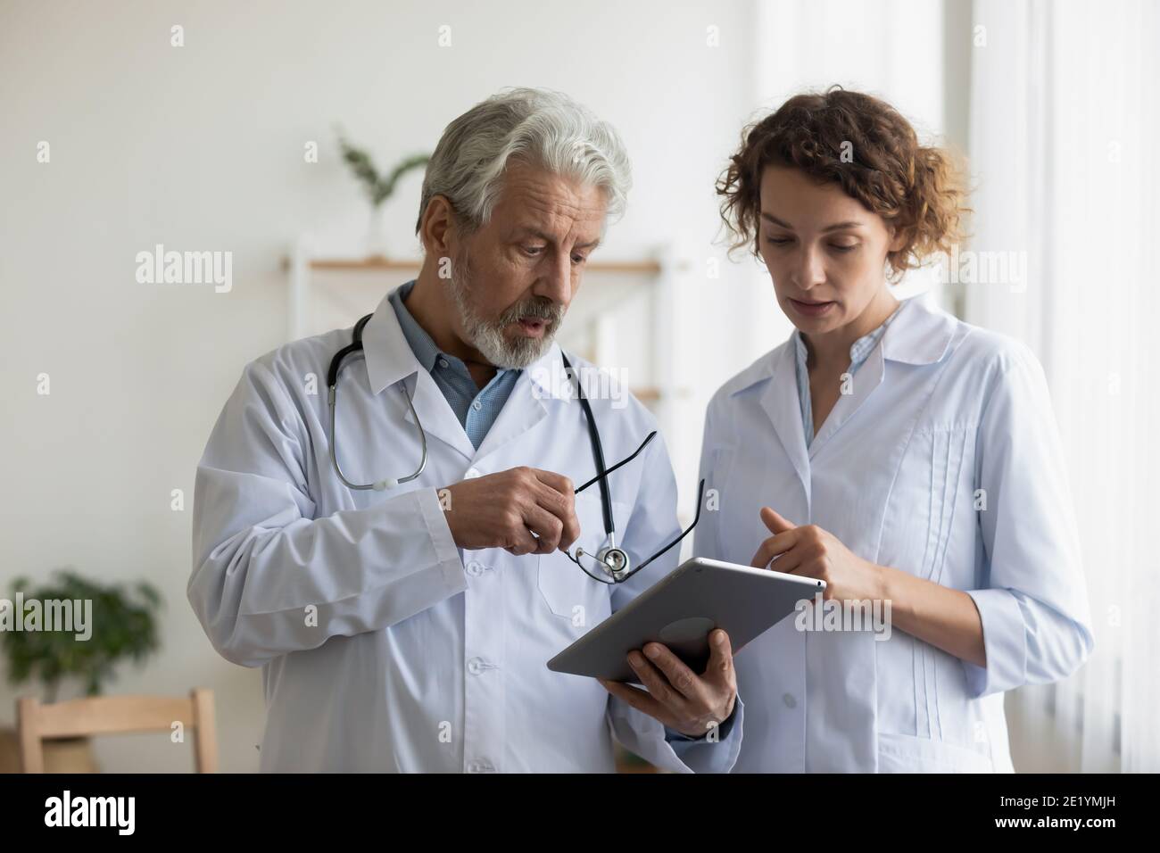 Serious alten männlichen Arzt diskutieren Testergebnisse mit jungen Kollegen. Stockfoto