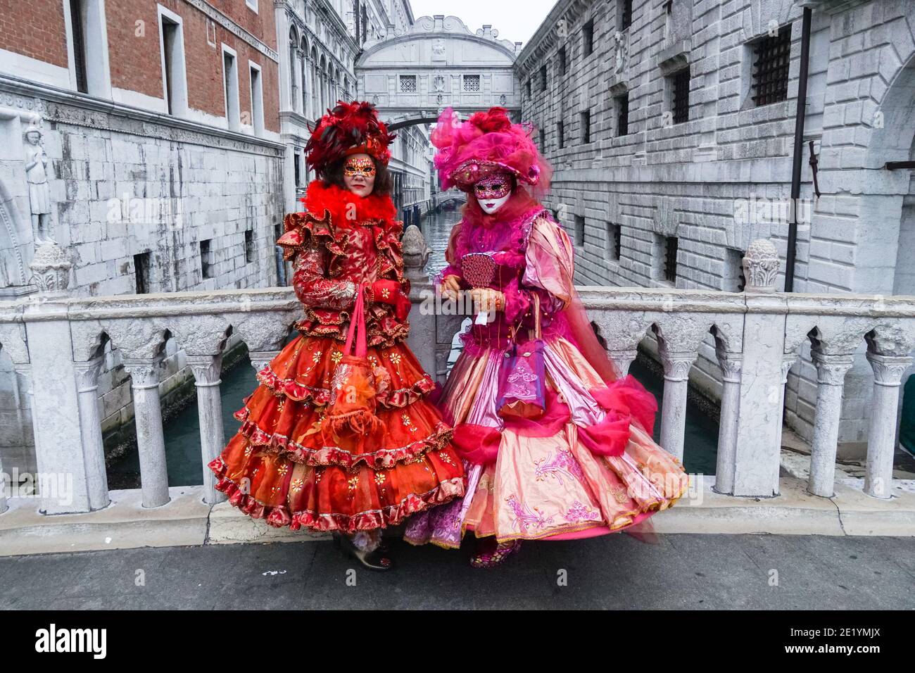 Zwei Frauen in traditionell dekorierten Kostümen und bemalten Masken während des Karnevals in Venedig mit der Seufzerbrücke dahinter, Venedig, Italien Stockfoto