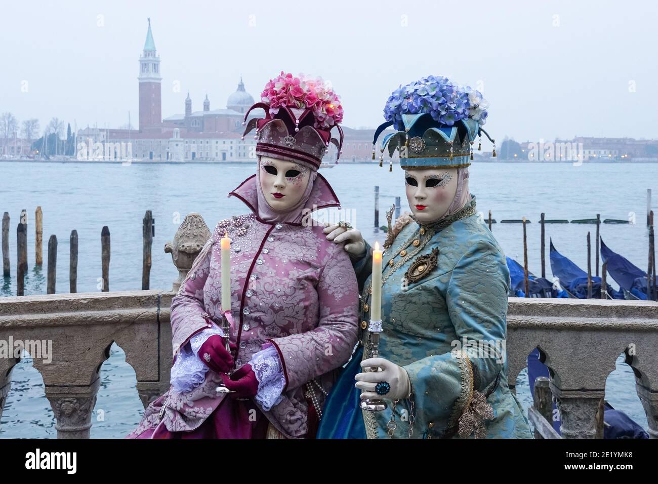 Frau in traditionell dekoriertem Kostüm und Maske während des Karnevals in Venedig gekleidet mit dem Kloster San Giorgio im Hintergrund Venedig, Italien Stockfoto