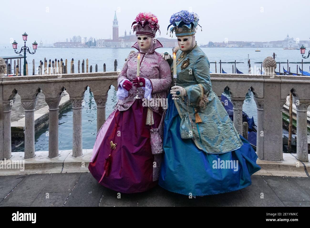 Frau in traditionell dekoriertem Kostüm und Maske während des Karnevals in Venedig gekleidet mit dem Kloster San Giorgio im Hintergrund Venedig, Italien Stockfoto