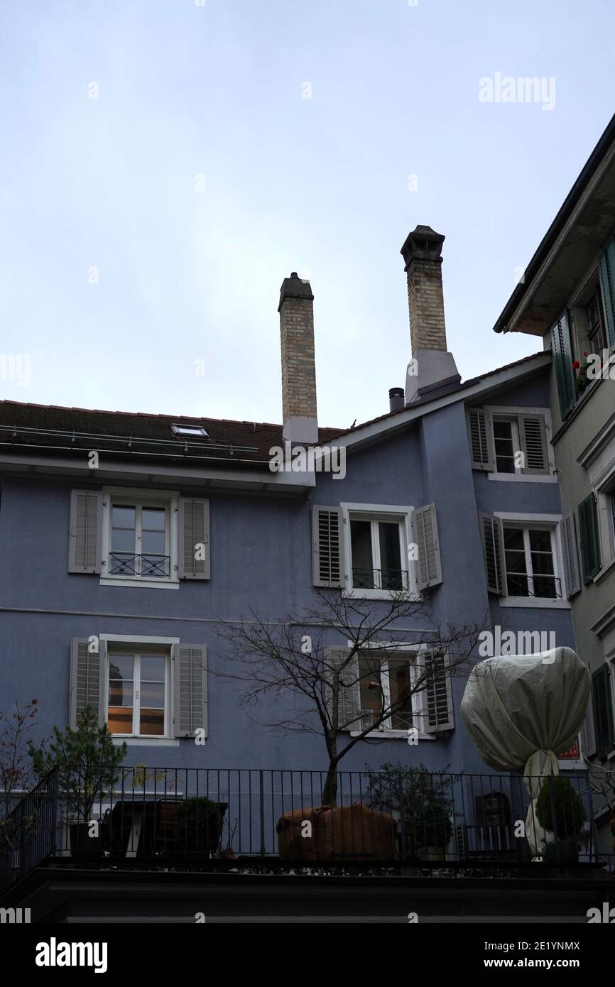 Ein Haus im Zentrum von Zürich mit einer großen Terrasse im Winter. Es gibt einige Pflanzen und Bäume. Einer von ihnen ist bedeckt, um es vor der Kälte zu schützen Stockfoto