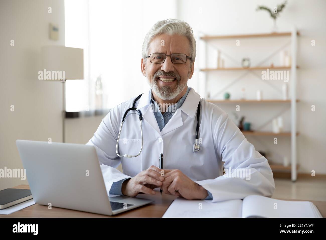 Porträt eines lächelnden vertrauenswürdigen Arzt mittleren Alters am Arbeitsplatz. Stockfoto