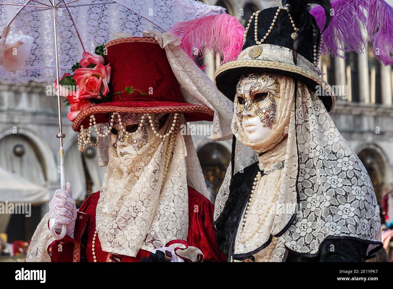 Menschen, die während des Karnevals in Venedig, Italien, in traditionell dekorierten Kostümen und bemalten Masken gekleidet waren Stockfoto