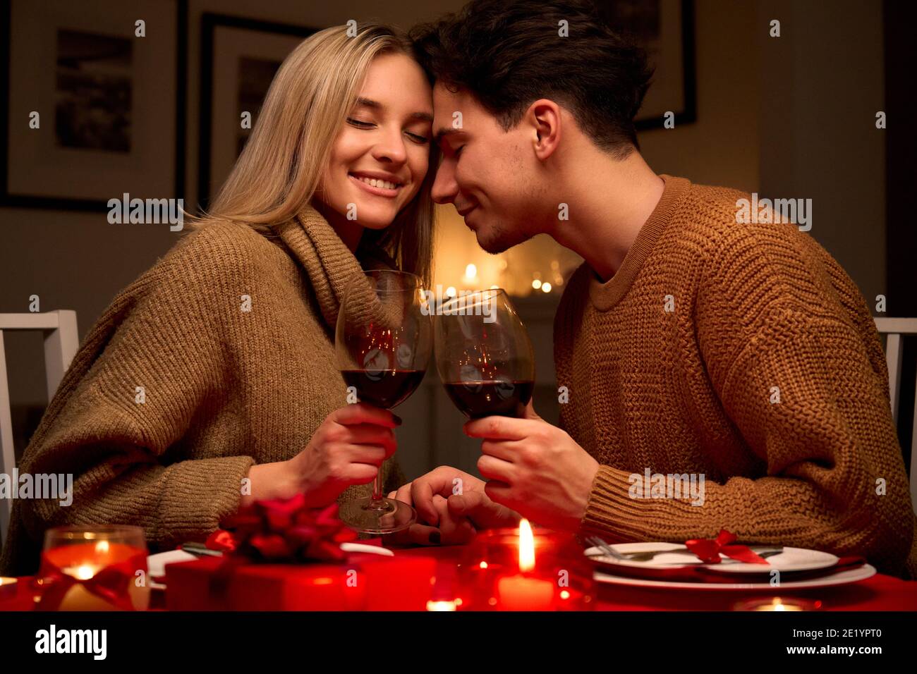 Glückliches Paar in der Liebe klirrende Gläser trinken Rotwein mit romantischen Abendessen. Stockfoto