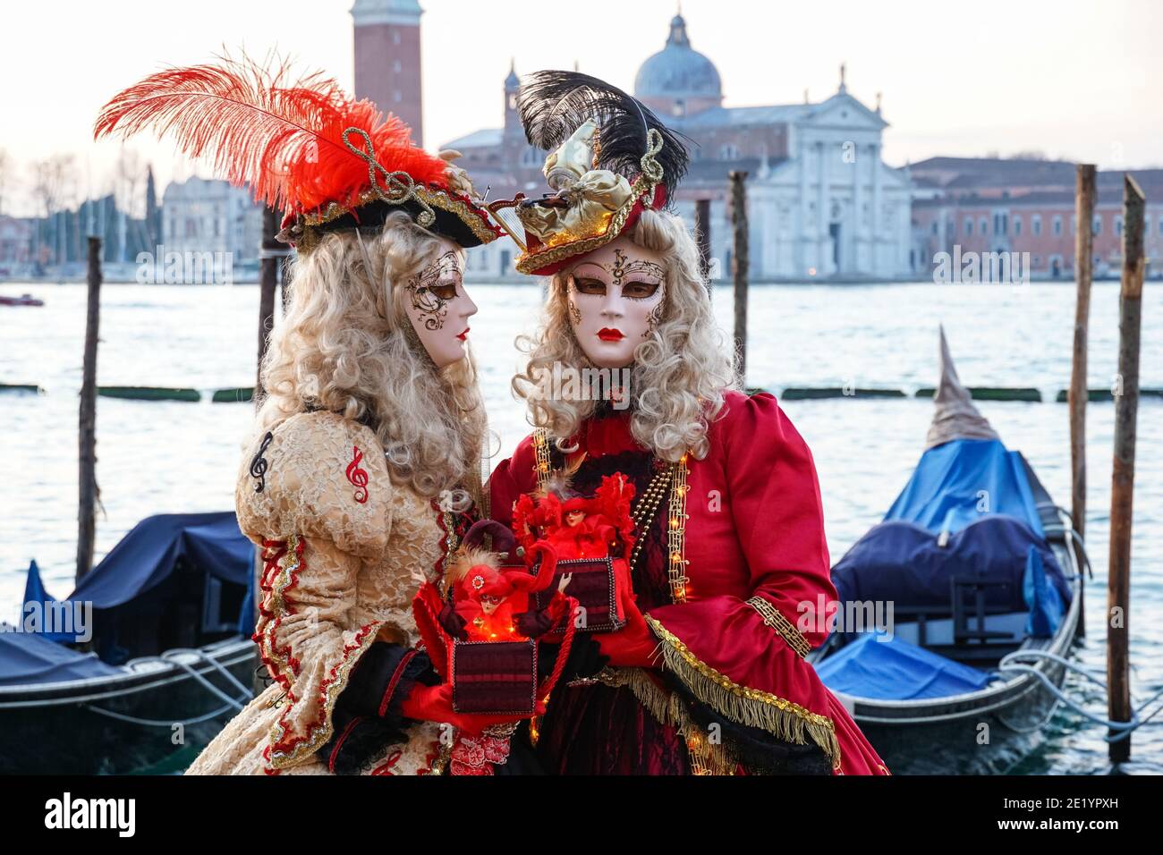 Zwei Frauen in traditionell dekorierten Kostümen und bemalten Masken während des Karnevals in Venedig mit dem Kloster San Giorgio hinter Venedig, Italien Stockfoto