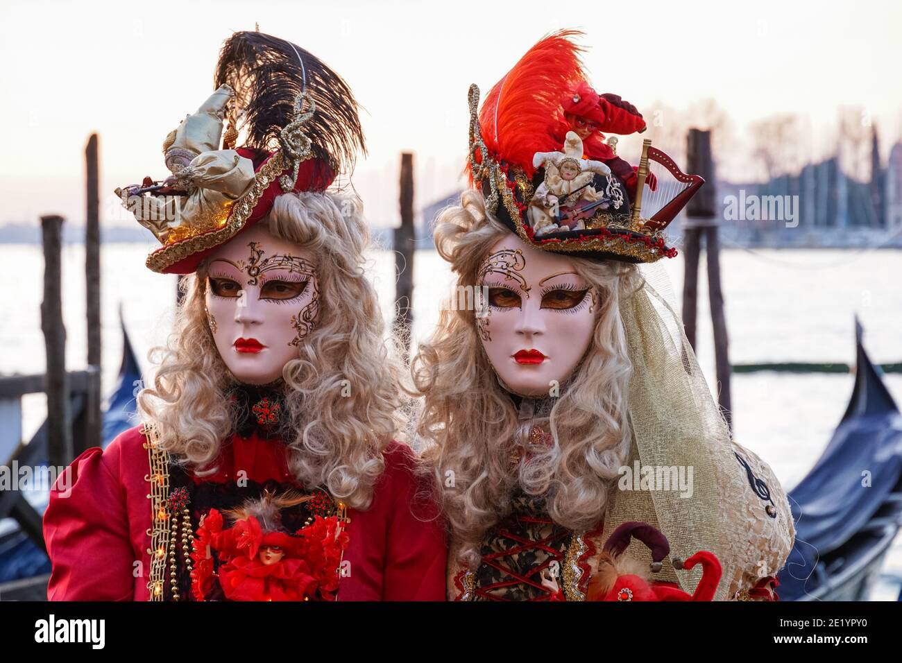 Zwei Frauen in traditionell dekorierten Kostümen und bemalten Masken während des Karnevals in Venedig mit dem Kloster San Giorgio hinter Venedig, Italien Stockfoto