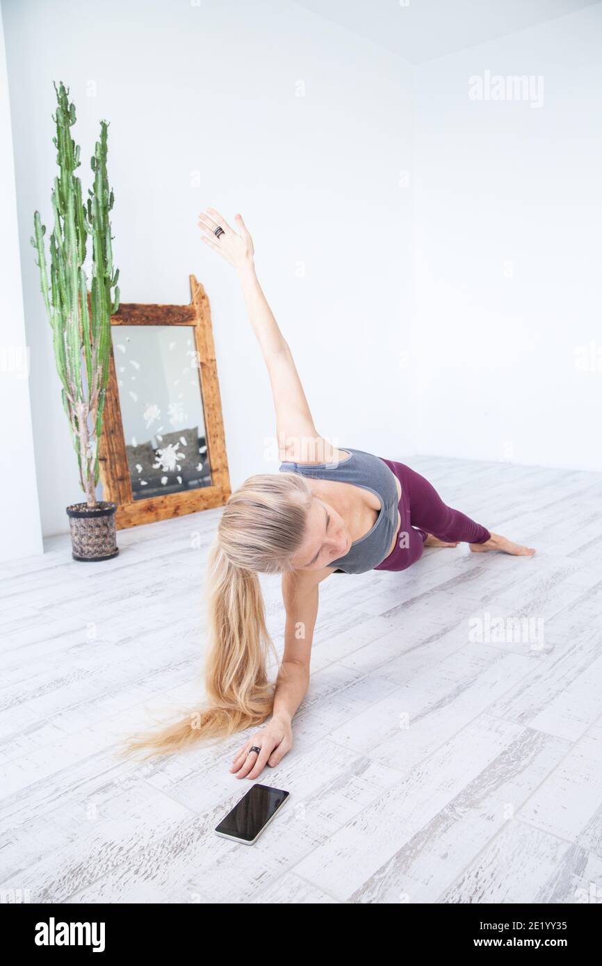 Fröhliche Sportlerin dabei Plank Übung in der Nähe von Smartphone Stockfoto