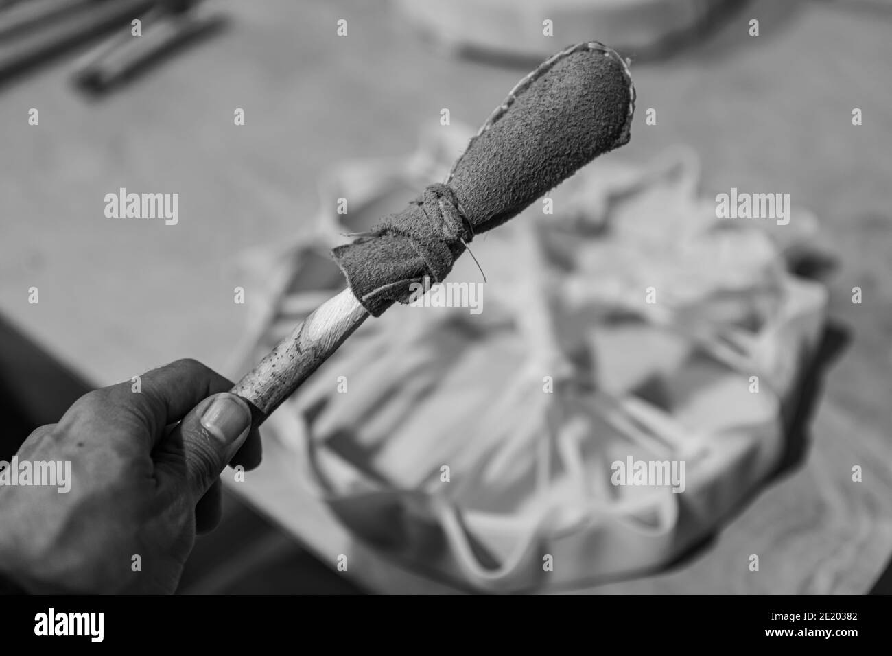 Schwarz-weiß Nahaufnahme eines kürzlich fertiggestellten, handgefertigten Schlagzeugstäbels mit Kopf in weichem Leder, der während einer einheimischen Trommelwerkstatt entstanden ist. Stockfoto