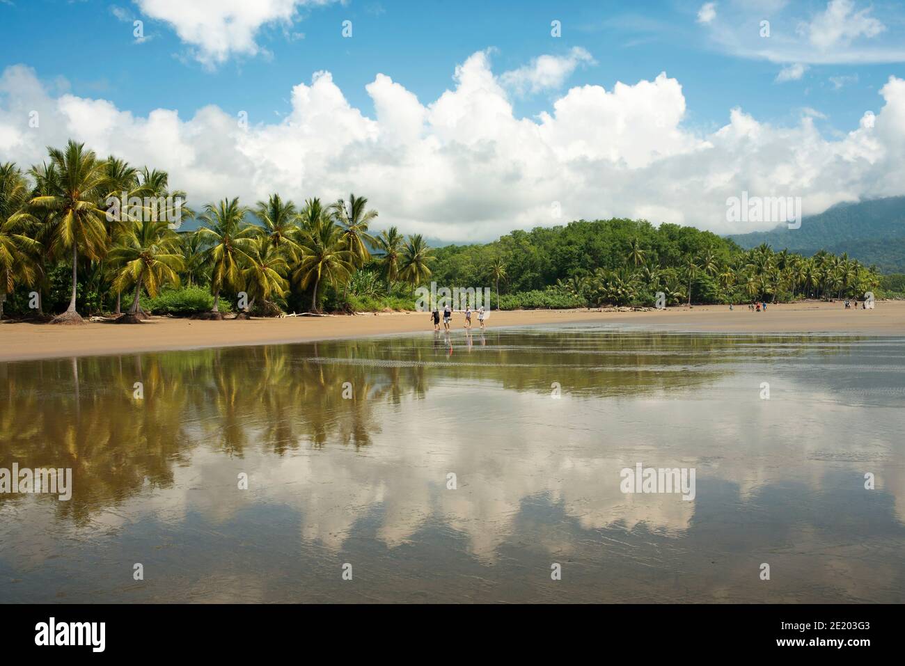 Wolkenspiegelungen im Gezeitenwasser und einige Wandertouristen. Nationalpark Marino Ballena, Bahia Ballena, Uvita, Costa Rica. November 2018 Stockfoto