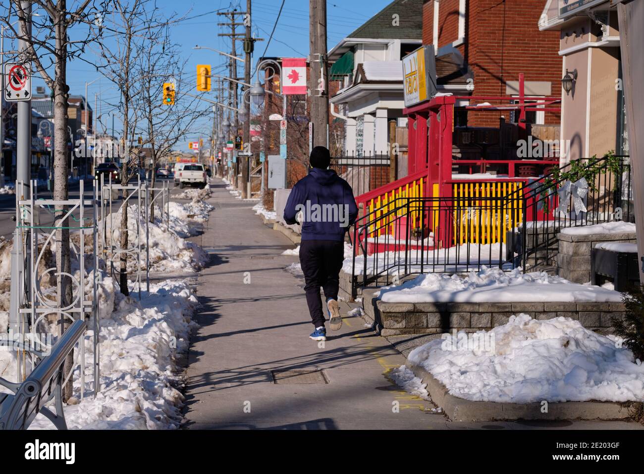 Männlicher Läufer, der auf dem Schnee weglief, gerodeten Bürgersteig auf einem Sonniger Wintertag in Ottawa Stockfoto