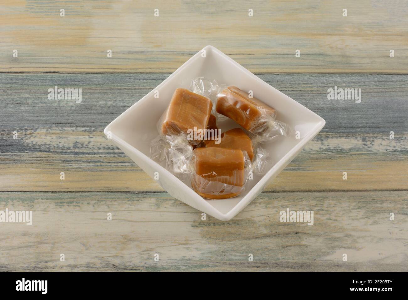 Gesalzene Karamell Süßigkeiten Stücke in klaren transparenten Süßigkeiten Wrapper n Weiße Süßigkeitenschale auf dem Tisch Stockfoto