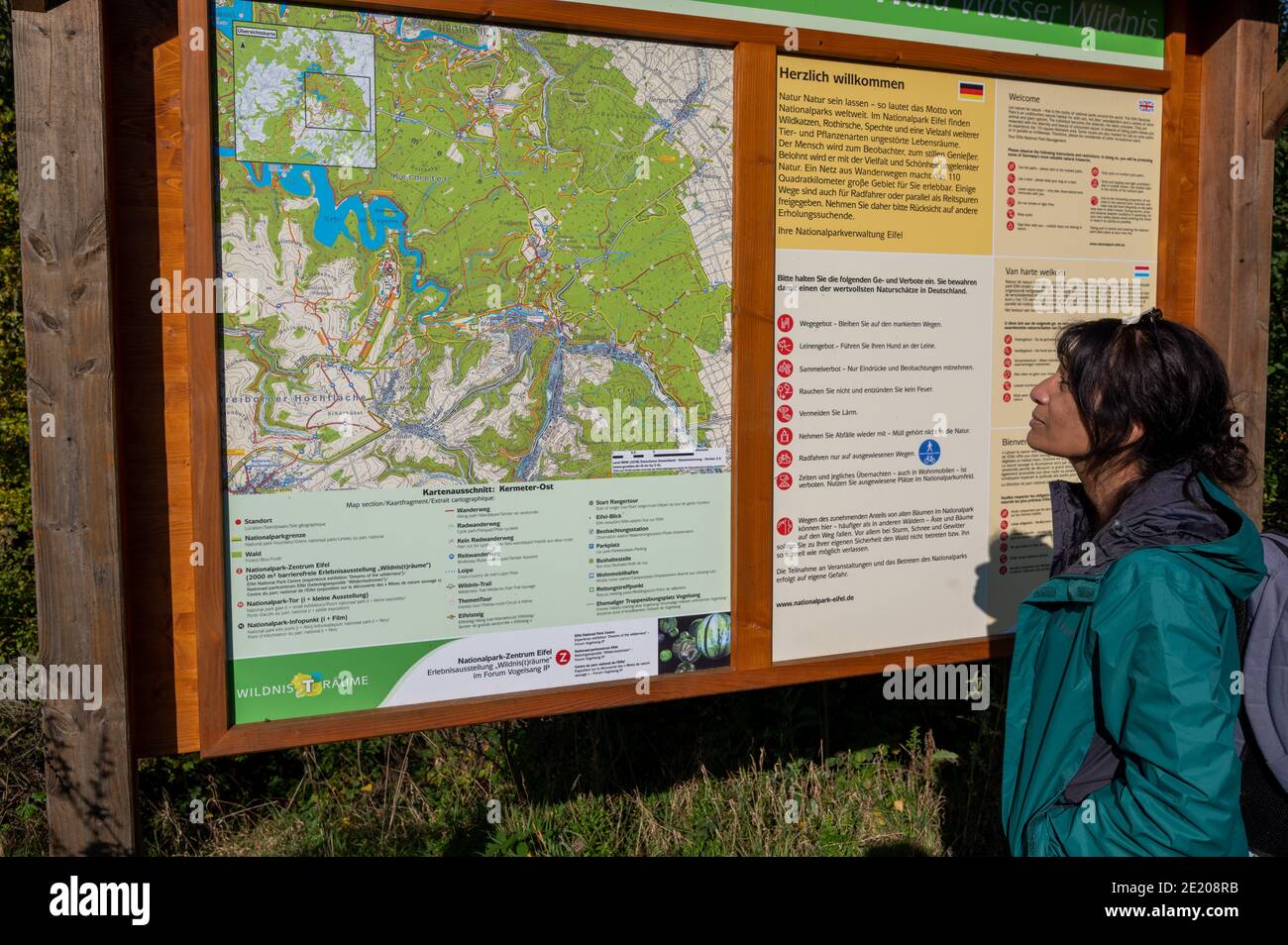 Asiatin beim Wandern im Nationalpark Eifel in Südwestdeutschland liest mehrsprachiges Informationsschild. Stockfoto