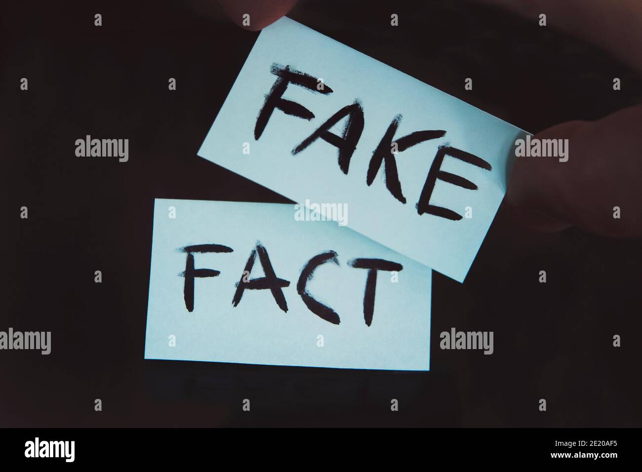 Tatsache oder gefälschtes Konzept, Veränderung. Substitution von Konzepten. Die Tatsache wird durch eine Fälschung ersetzt. Ein Mann ändert die Zeichen mit den Worten Fakt auf Fake auf einem schwarzen Stockfoto