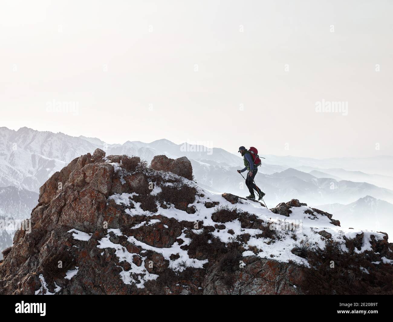 Mann mit Rucksack zu Fuß auf dem Felsen in der schönen Berge bei Sonnenuntergang Hintergrund Stockfoto