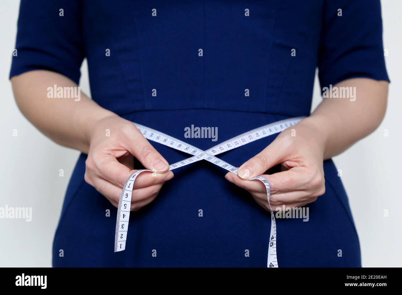 Gewichtsverlust, Schlankheitskur, Diät-Konzept. Frau in blauem Kleid mit Maßband um die Taille Stockfoto