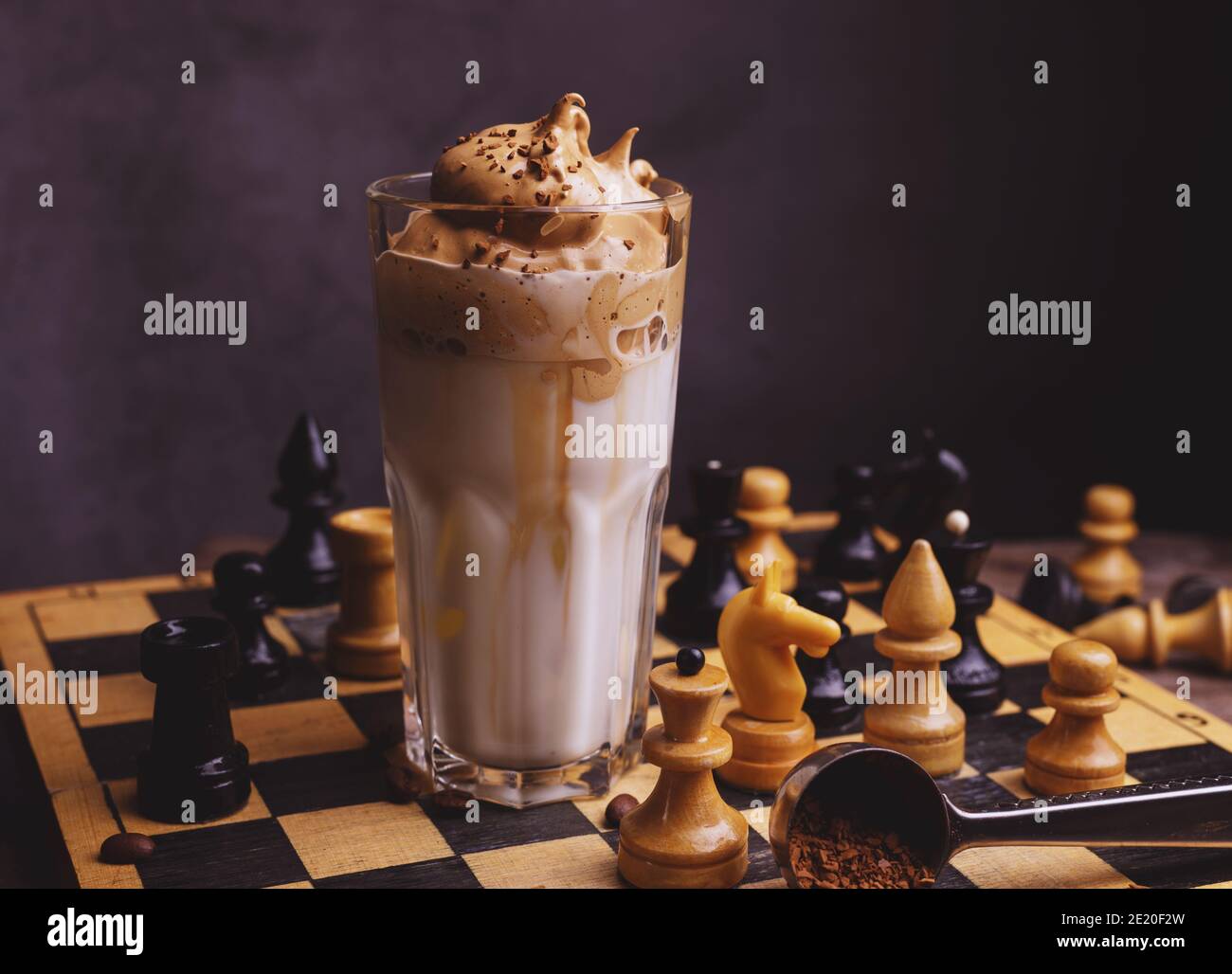 Dalgona Kaffee. Schlagsahngetränk mit Instant-Kaffee beliebt in Korea cremigen Cocktail in hohen Gläsern mit Schach auf Holzchessboard dekoriert Stockfoto