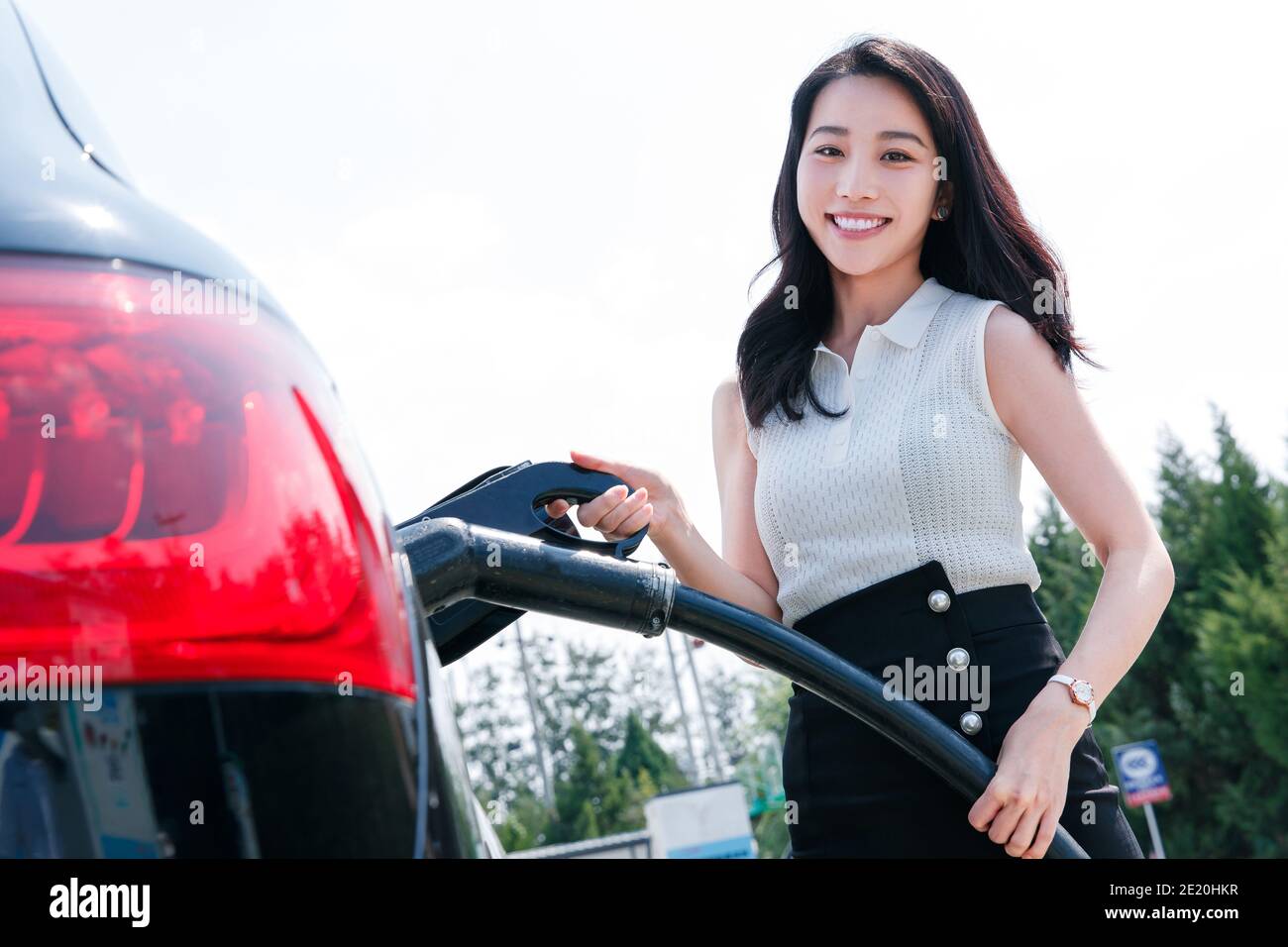 Eine schöne junge Frau zu Autobatterie Stockfoto