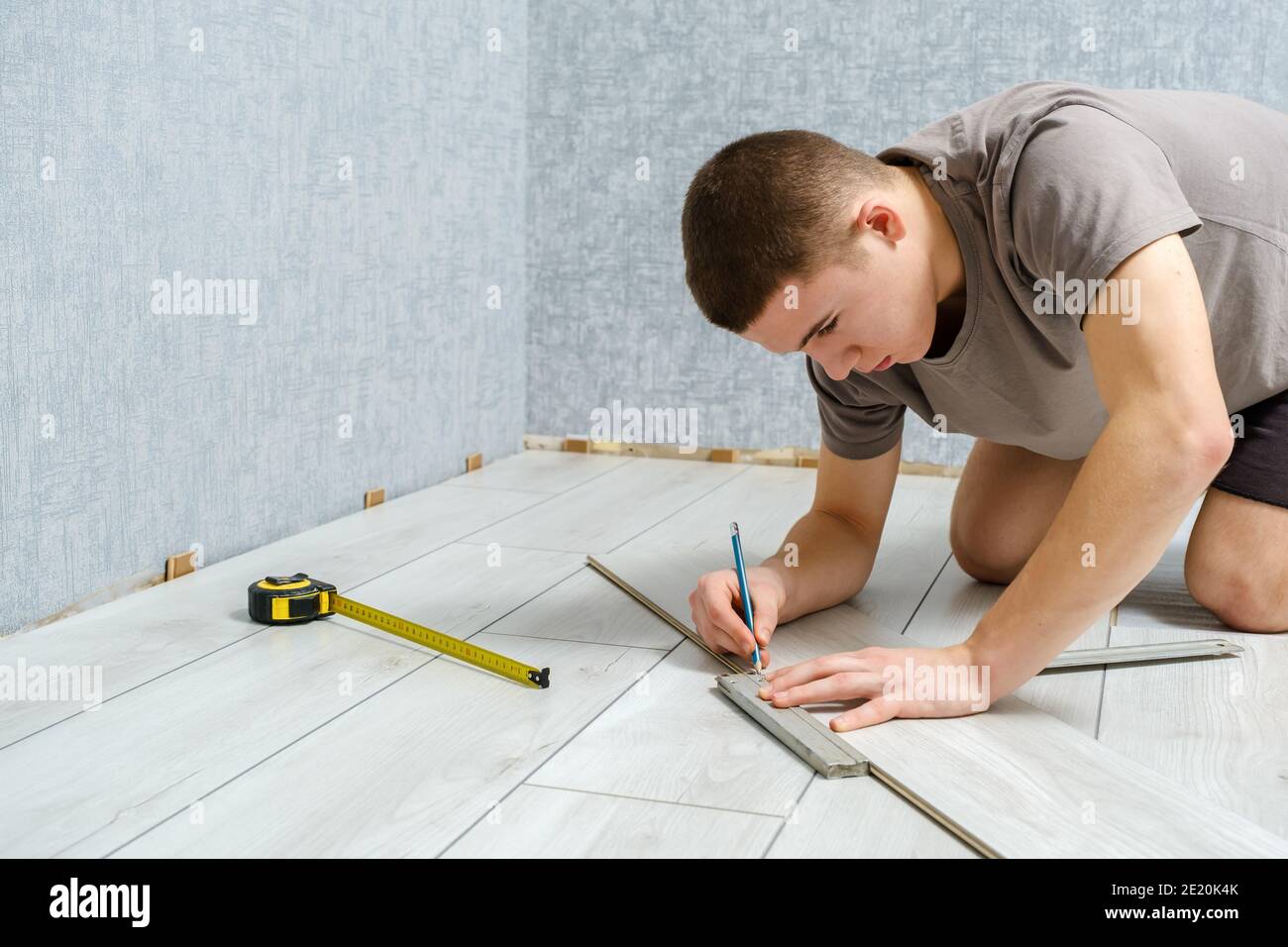 Der junge Mechaniker markiert eine Holzplatte mit einem Bleistift Und Lineal vor dem Schneiden Stockfoto