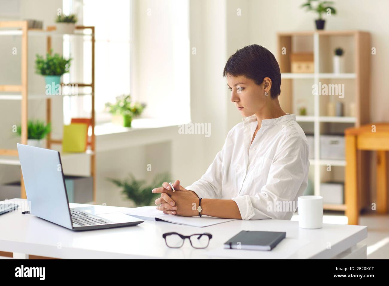 Junge Frau, die sich ein Schulungsvideo ansieht oder an einem Webinar mit einem Laptop teilnimmt Computer Stockfoto