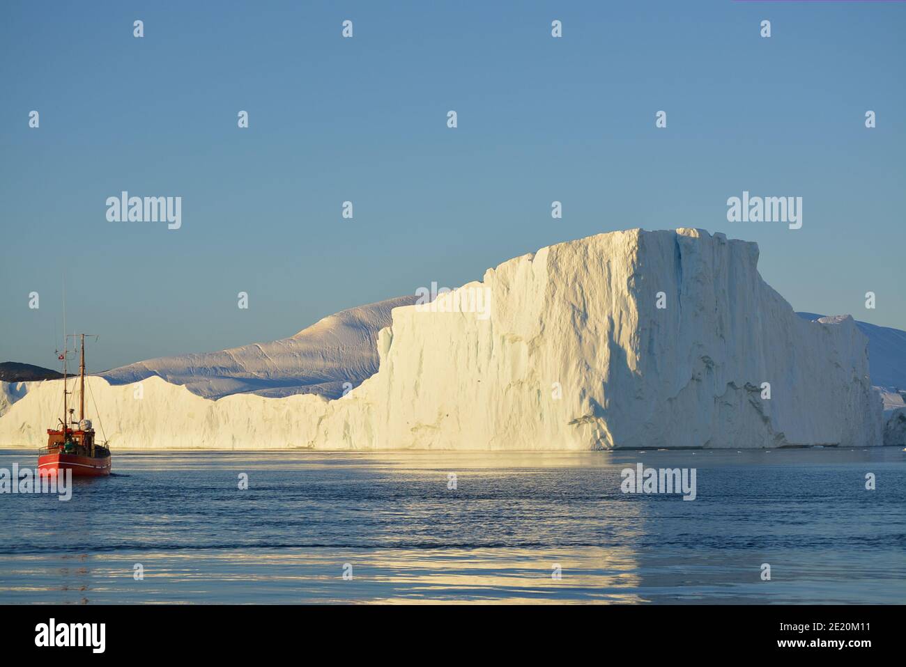 Kleines Boot zwischen riesigen Eisbergen in der Disko Bay, Ilulissat icefjord in der Mitternachtssonne im Juli, Welterbe durch den Klimawandel beeinflusst Stockfoto