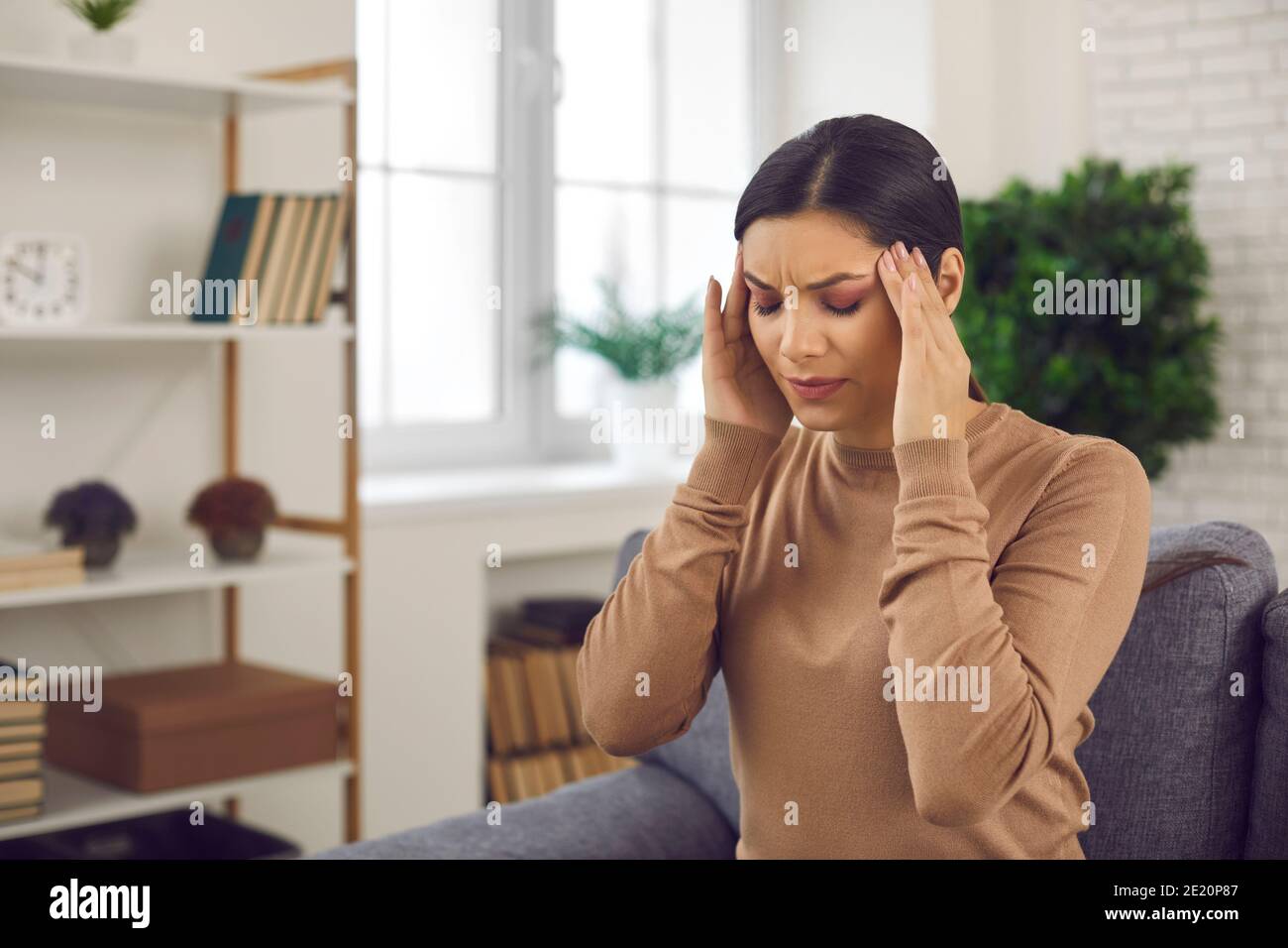 Frau berührt ihre Schläfen, leidet unter Stress, Kopfschmerzen oder schwerer Migräne Stockfoto