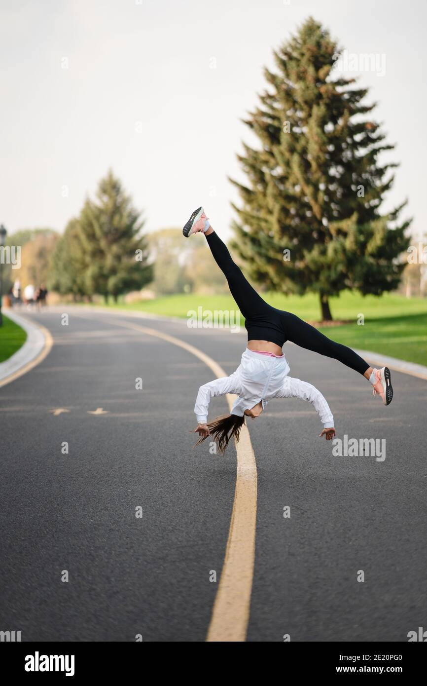 Frau Sportlerin springt auf die Straße und macht Übungen im Freien. Stockfoto