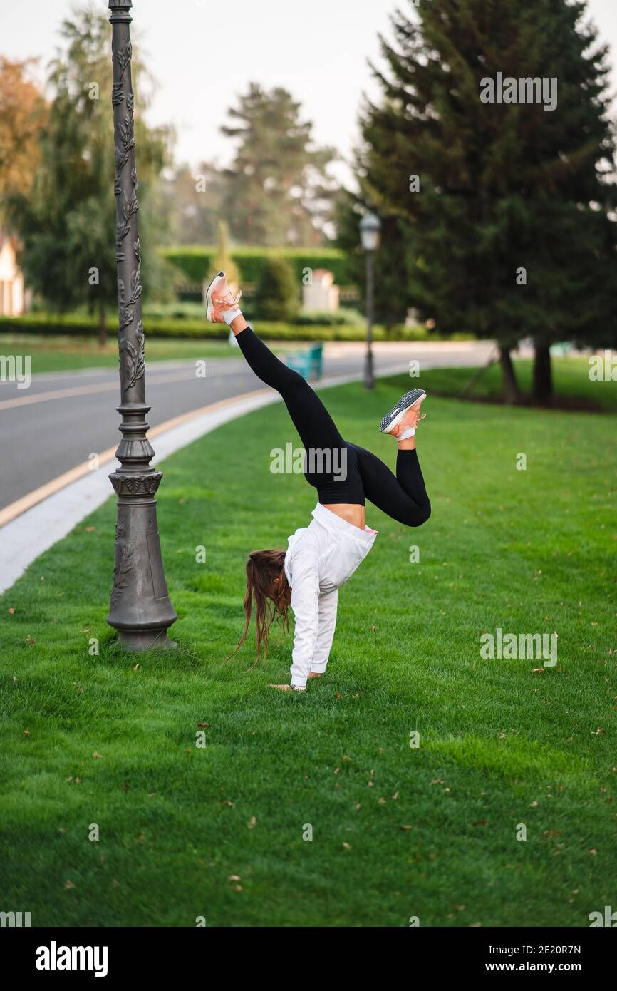 Attraktive dünne Frau tut einen Backbend, während sie einen Salto zeigt. Stockfoto