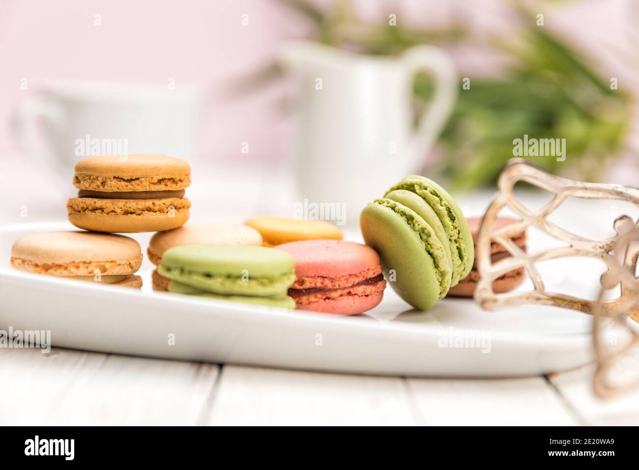 Verschiedene französische Macarons auf einem Teller mit Teigzange auf dem Couchtisch, geringe Schärfentiefe Stockfoto
