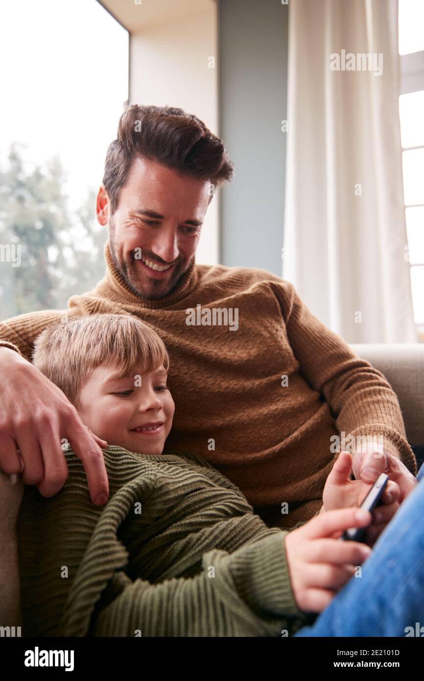 Vater Und Sohn Auf Sofa Zu Hause Mit Spaß Spielen Spiel Auf Dem Handy Stockfoto