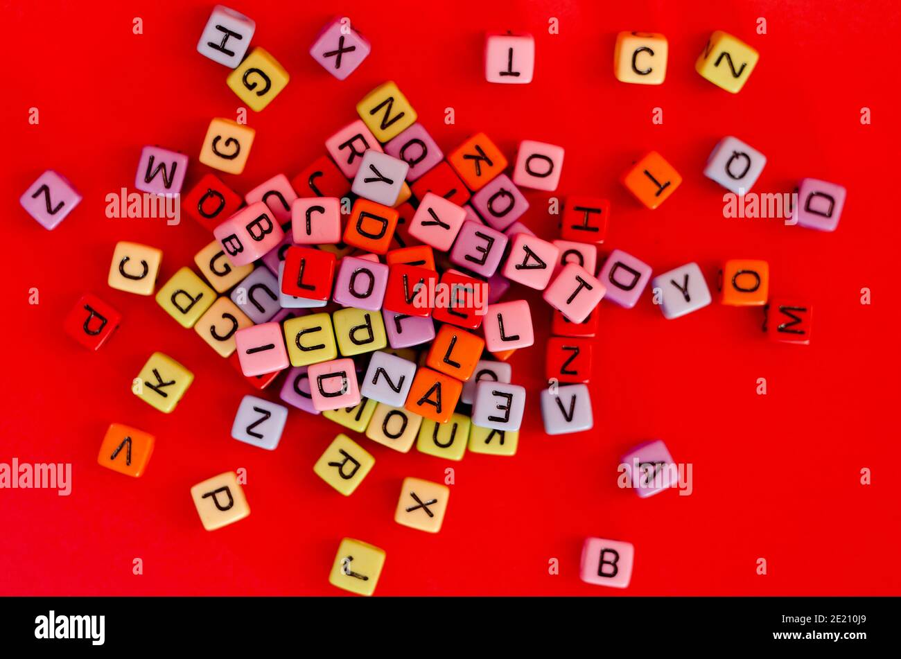 Bunte Holzwürfelperlen mit Buchstaben auf rotem festlichem Hintergrund, Wort "Liebe". Valentinstag. 14 Februar. Flach liegend, Draufsicht. Stockfoto