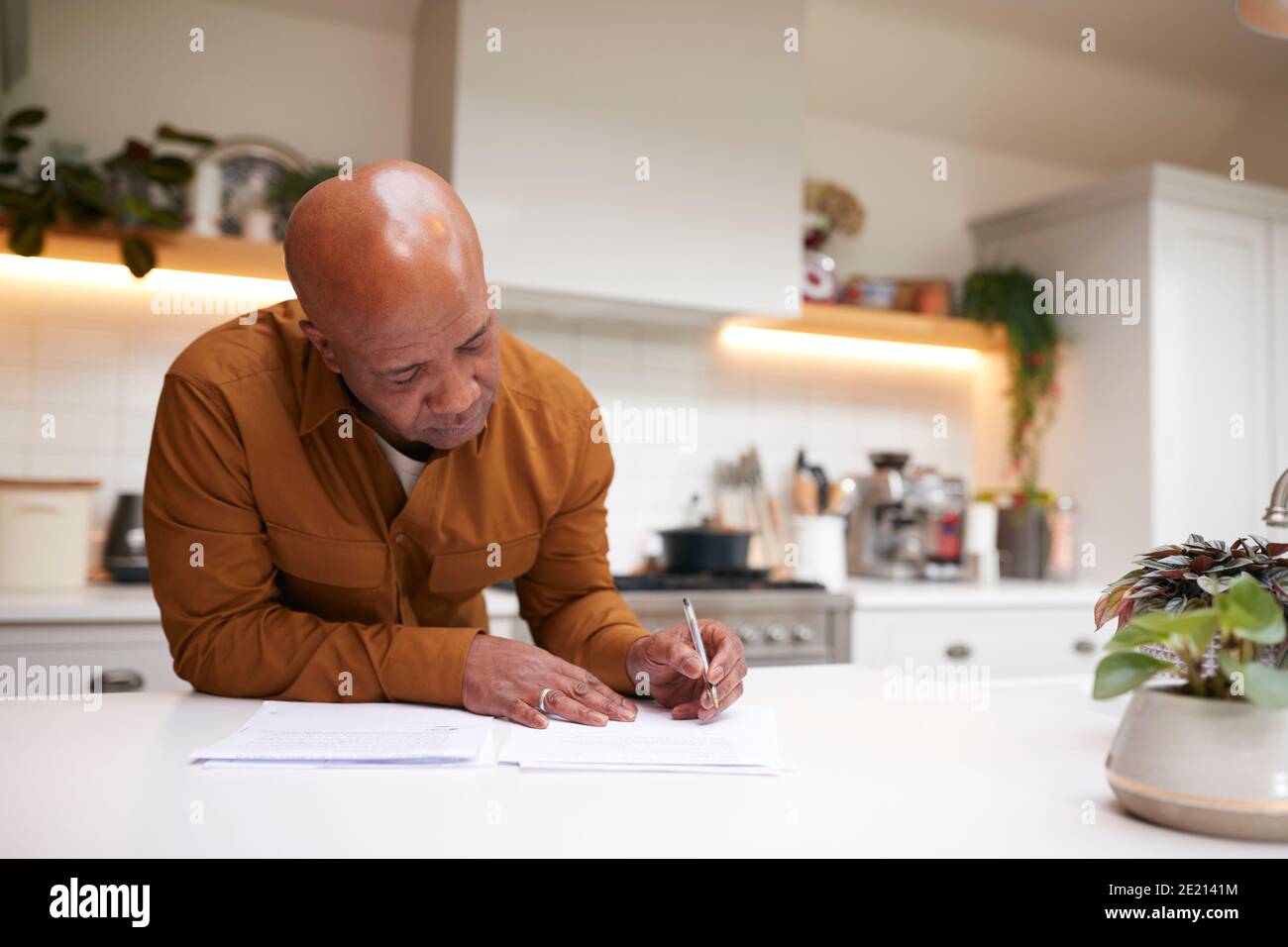 Reifer Mann Überprüfung Und Unterzeichnung Inländischen Finanzen Und Investitionen Papierkram In Der Küche Zu Hause Stockfoto