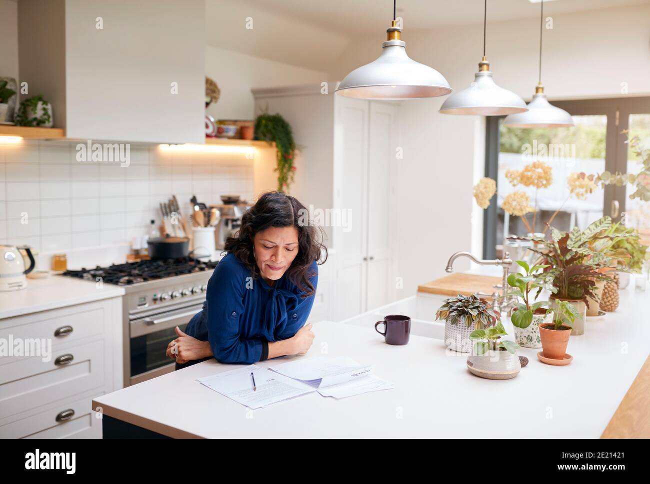 Reife Frau Überprüfung Und Unterzeichnung Inländischen Finanzen Und Investitionen Papierkram In Der Küche Zu Hause Stockfoto