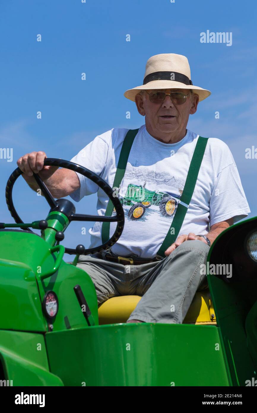 Mann fährt Traktor und trägt Traktor T-Shirt auf New Forest & Hampshire County Show, Brockenhurst, Hampshire, Großbritannien im Juli Stockfoto
