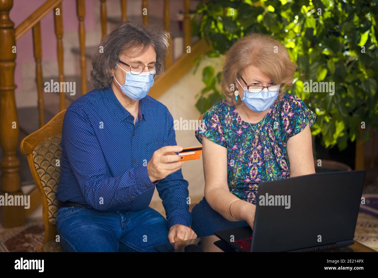 Ältere Paar mit Gesichtsmaske auf Urlaub Online-Shopping während Sitzen in der Hotellobby Stockfoto