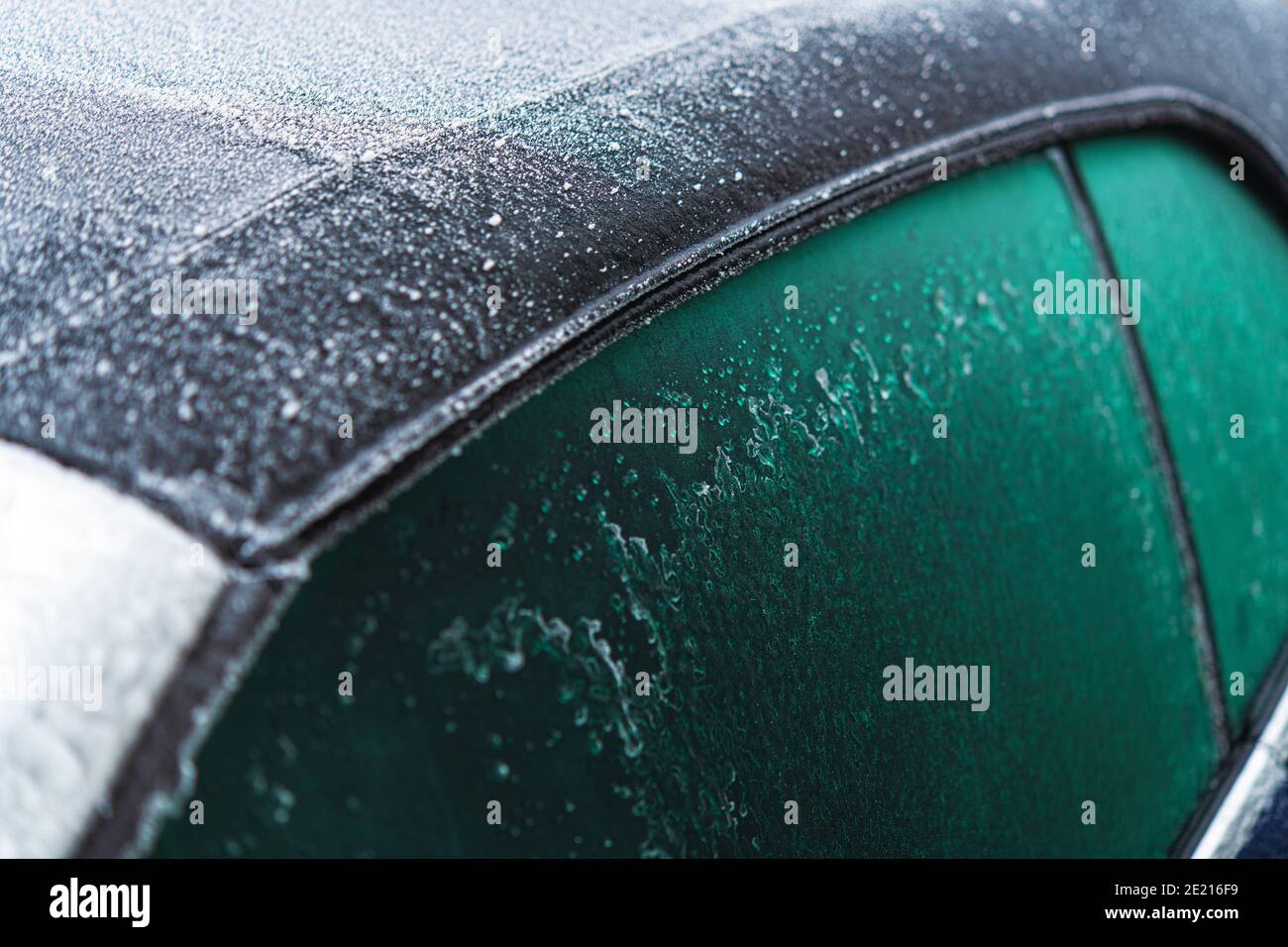 Modernes Cabrio-Fahrzeugdach aus Stoff, das bei extrem niedrigen Temperaturen von Eis und eisigen Regen bedeckt ist. Cabriolet Winter Driving Thema. Stockfoto