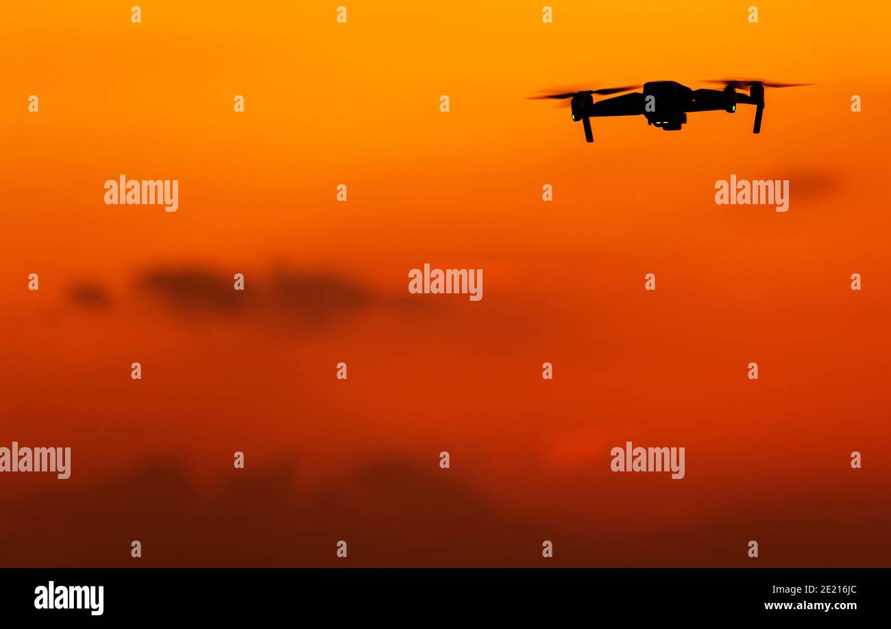 Moderne Lufttechnik. Unbemannte Luftfahrzeug Drohne auf dem rötlichen Sonnenuntergang Himmel. Großer Kopierbereich. Stockfoto