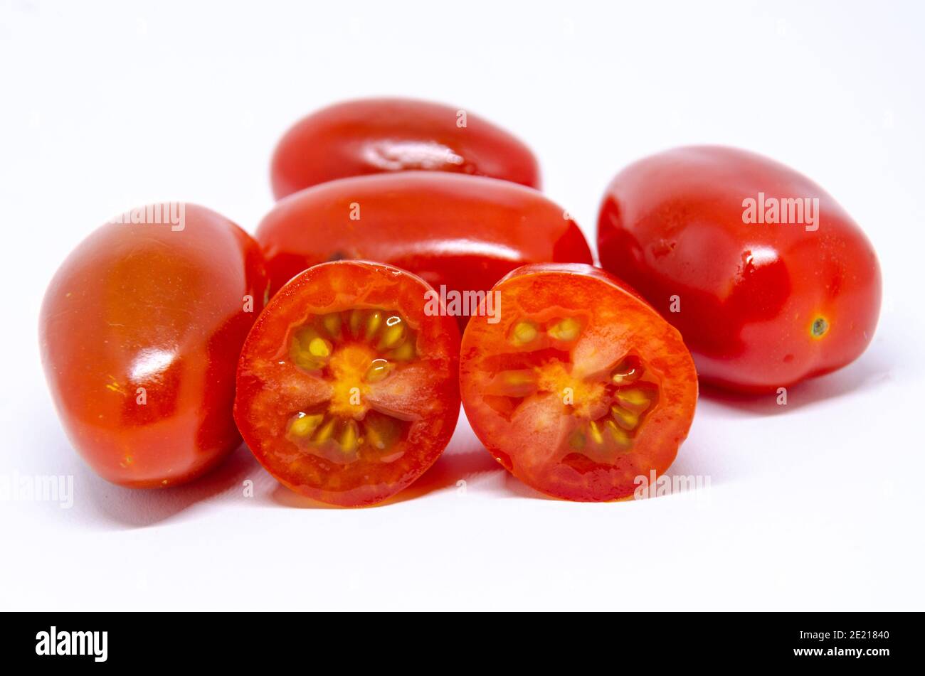 Baby plumb Tomaten isoliert auf einem weißen Hintergrund. Einer wurde halbiert und zeigt die Samen darin. Stockfoto