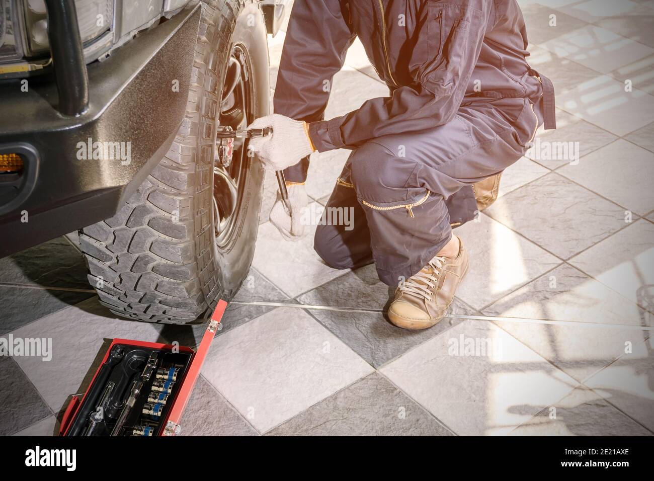 Kfz-Reparaturarbeiter tragen dunkelblaue Uniformen sind mit Werkzeugen, um die Radmuttern zu entfernen, um zu überprüfen und zu reparieren in der Auto-Reparatur-Center. Stockfoto