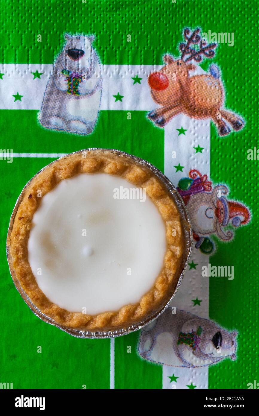 iced topped Mince Pie von Sainsburys auf festlicher Serviette mit Weihnachtsserviette - Konditoreien gefüllt mit Hackfleisch, gekrönt mit weicher weißer Fondant-Vereisung Stockfoto