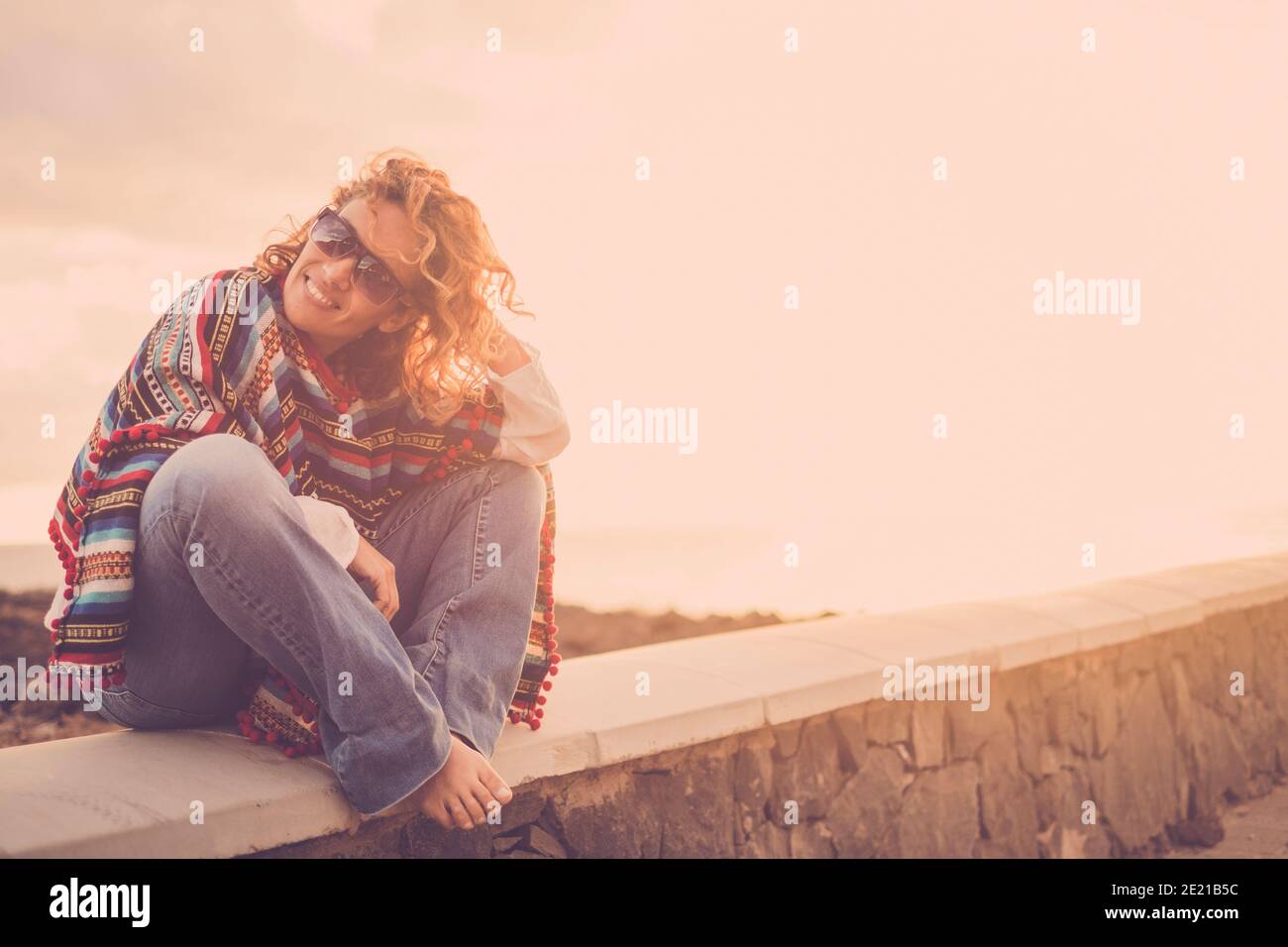 Frau sitzen im Freien genießen Sonnenuntergang und Freiheit allein mit Ein Lächeln - Porträt von fröhlichen weiblichen kaukasischen Menschen mit Trendige Kleidung und Mixeican Stockfoto