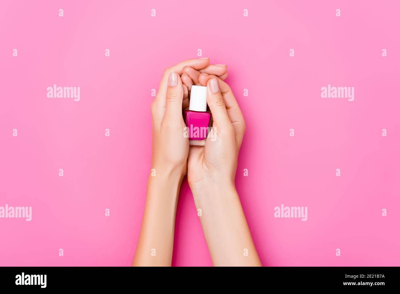 Beschnittene Ansicht der Frau, die eine Flasche mit glänzendem Nagellack hält Auf rosa Hintergrund Stockfoto