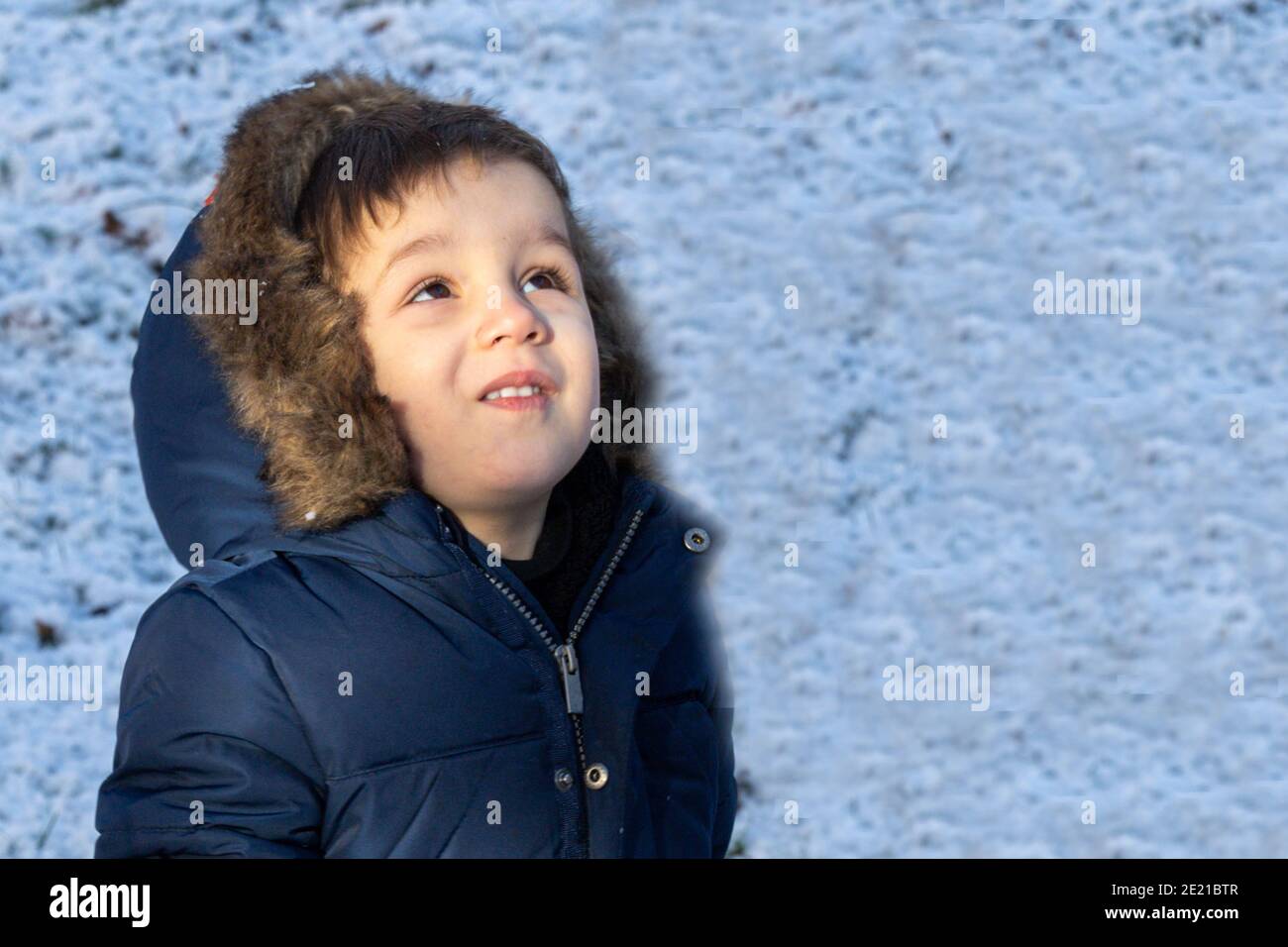 Porträt eines kleinen Jungen, der den Himmel geschützt betrachtet Für den kalten Winter Stockfoto