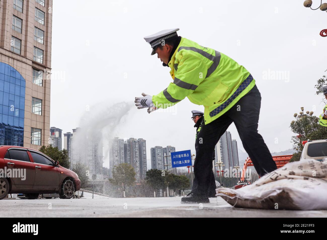 (210111) -- PANZHOU, 11. Januar 2021 (Xinhua) -- Verkehrspolizisten verbreiten industrielles Salz, ein Eisschmelzmittel, auf der Donghu-Brücke in der Stadt Panzhou im Südwesten Chinas, Provinz Guizhou, 11. Januar 2021. Die jüngste starke Kältewelle hat in Panzhou und vielen anderen Orten in Guizhou zu einer Staubildung geführt. Rund 400 Verkehrspolizisten in Panzhou arbeiten nun rund um die Uhr daran, die Straßenflächen der Eisverkleidungen in der Stadt zu entfernen. Das fluoreszierende Grün auf ihren Jacken scheint die wärmste Farbe in einem frostigen Winter zu sein. (Xinhua/Ou Dongqu) Stockfoto