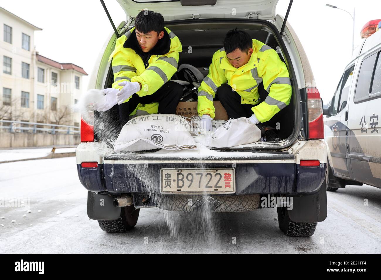 (210111) -- PANZHOU, 11. Januar 2021 (Xinhua) -- Verkehrspolizisten verbreiten industrielles Salz, ein Eisschmelzmittel, auf der Elangpu-Brücke in der Stadt Panzhou im Südwesten Chinas, Provinz Guizhou, 11. Januar 2021. Die jüngste starke Kältewelle hat in Panzhou und vielen anderen Orten in Guizhou zu einer Staubildung geführt. Rund 400 Verkehrspolizisten in Panzhou arbeiten nun rund um die Uhr daran, die Straßenflächen der Eisverkleidungen in der Stadt zu entfernen. Das fluoreszierende Grün auf ihren Jacken scheint die wärmste Farbe in einem frostigen Winter zu sein. (Xinhua/Ou Dongqu) Stockfoto